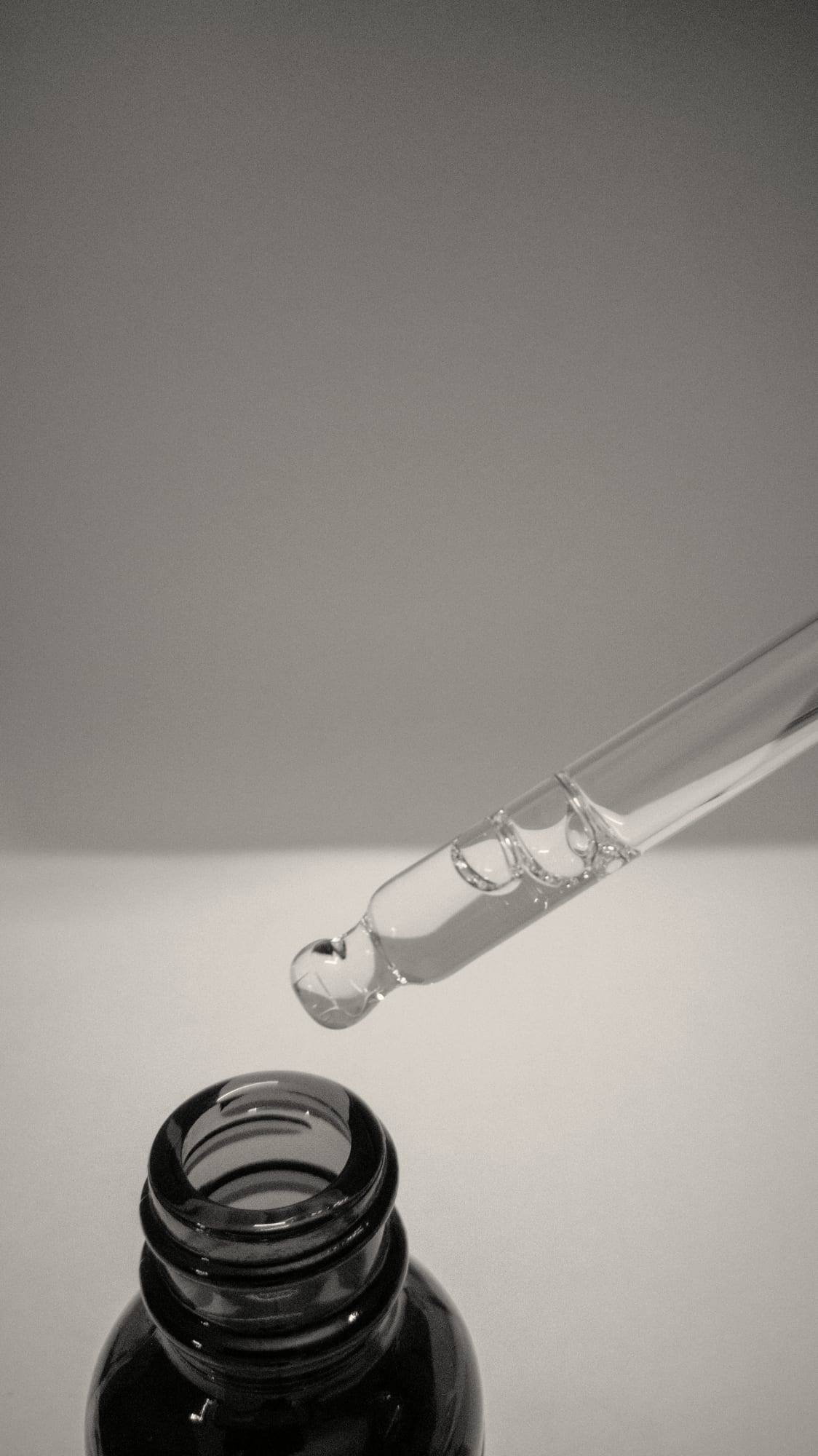 Koyu cam şişenin üstünde serum damlatan bir damlalık