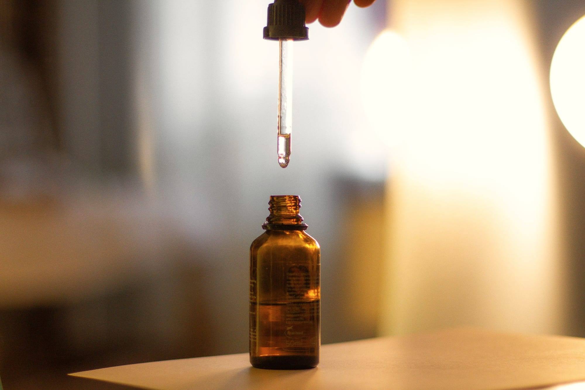 Sıcak ışıkta amber renkli şişeye serum damlatan bir damlalık